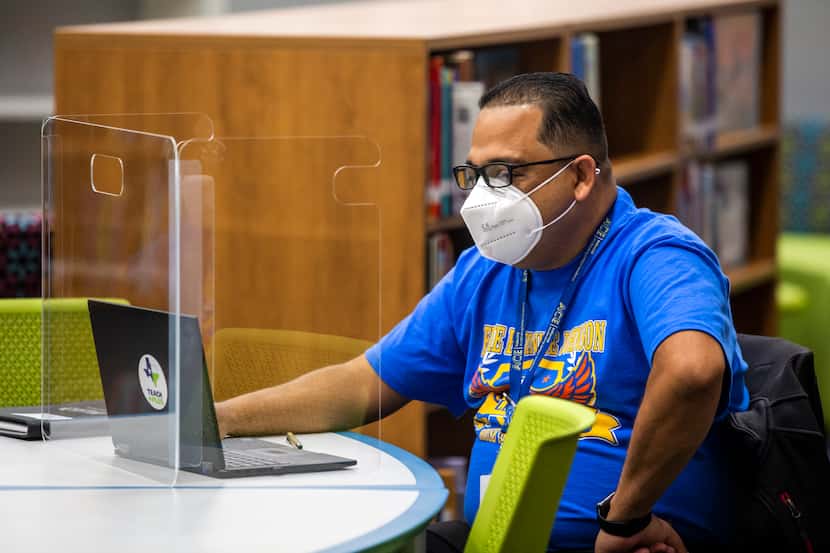 Third grade bilingual teacher Justo Echaverry sits in an empty library as he prepares to...