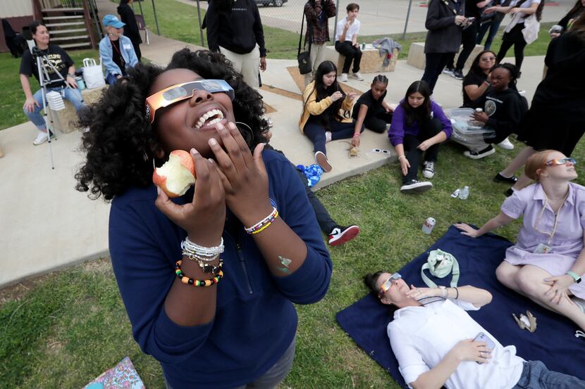 Eighth grader Brooklyn Bruff, 13, of Dallas enjoys an apple while viewing the total solar...