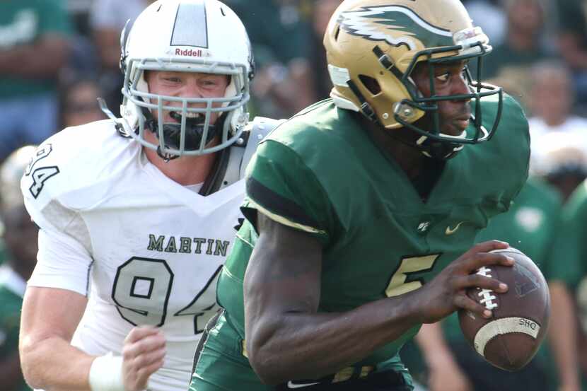 DeSoto Eagles quarterback Tristen Wallace (5) rolls out of the pocket to avoid the pressure...