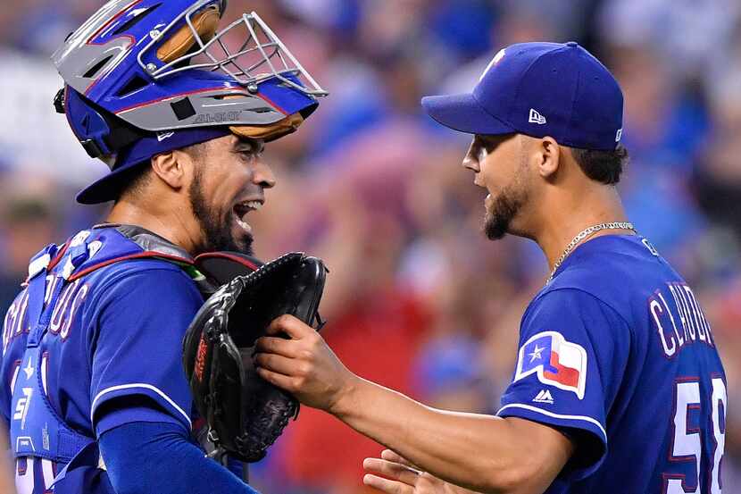 Texas Rangers catcher Robinson Chirinos and relief pitcher Alex Claudio celebrate the teams...