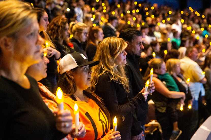 People gather for a candlelight vigil to honor the victims of a mass shooting in Thousand...