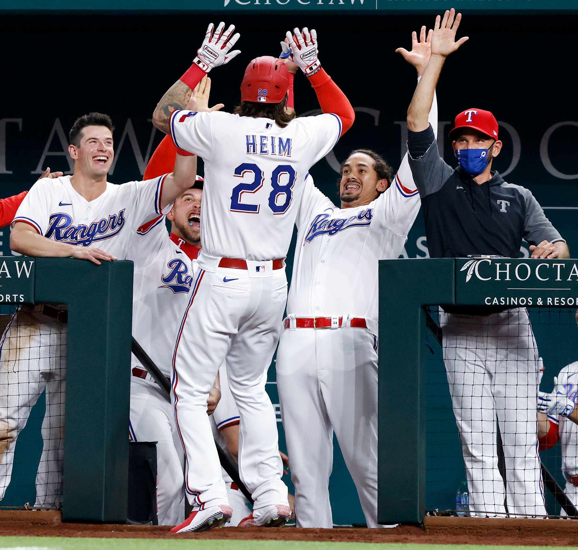 Texas Rangers Jonah Heim (28) is congratulated by manager Chris Woodward (right) and his...