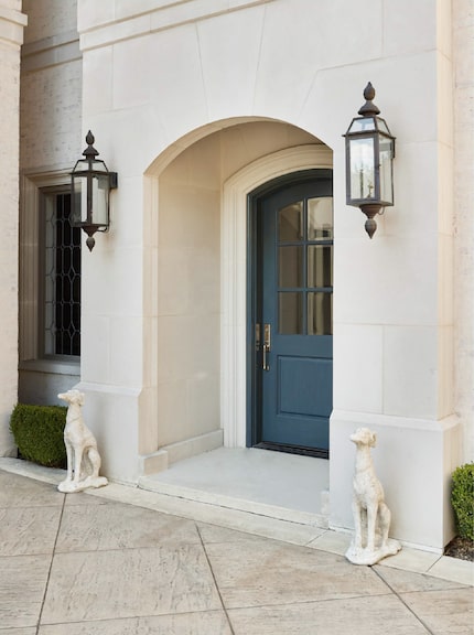 White stone doorway flanked by two dog statues and featuring a blue painted door