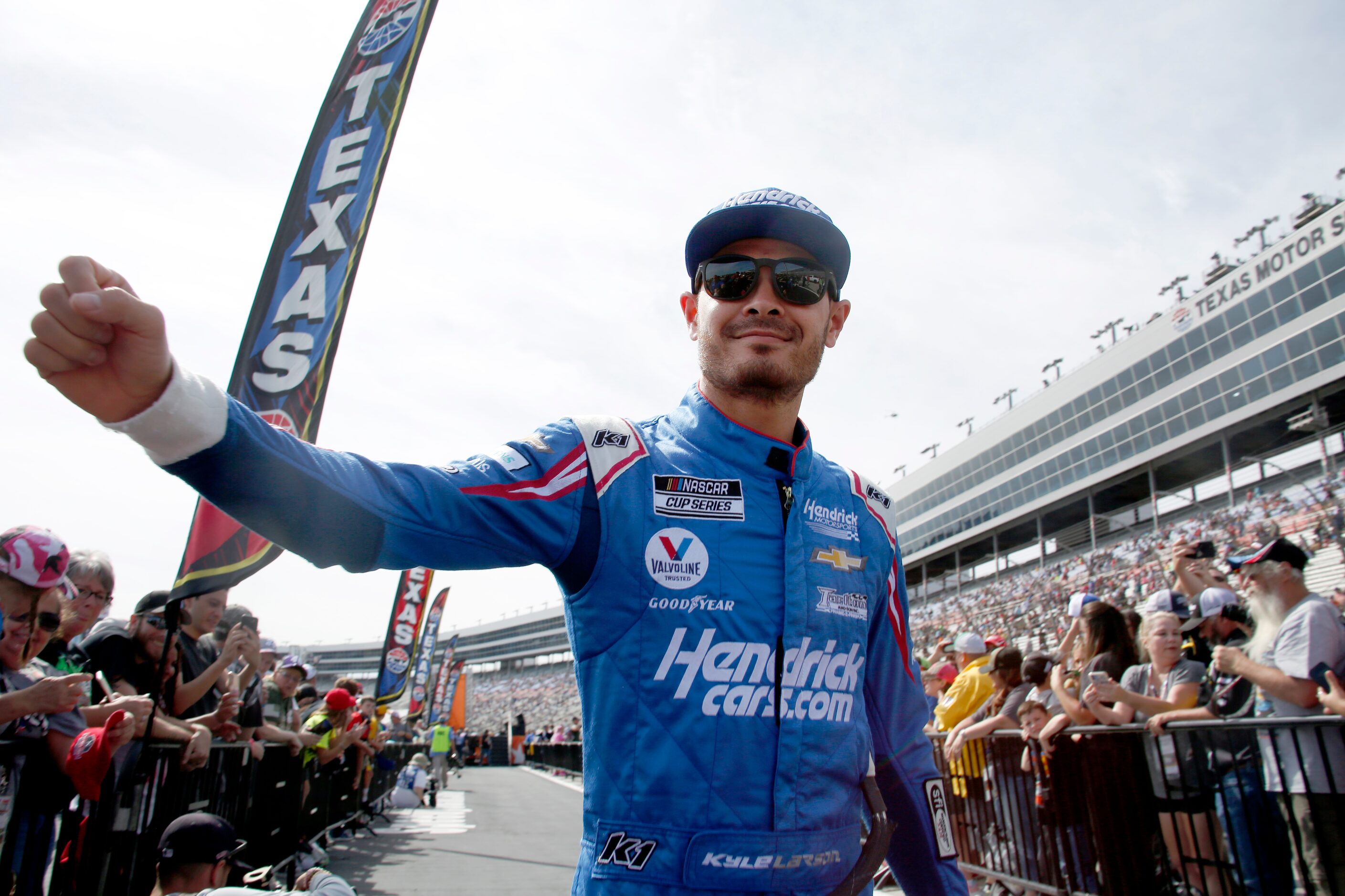 Driver Kyle Larson stretches to share a fist bump with a fan during driver introductions...