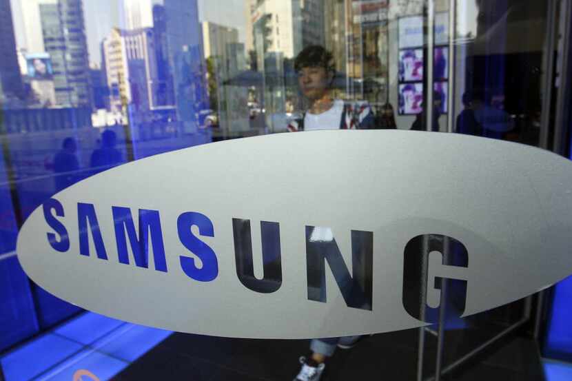 FILE - A visitor passes by the logo of Samsung Electronics Co. at a showroom of its...