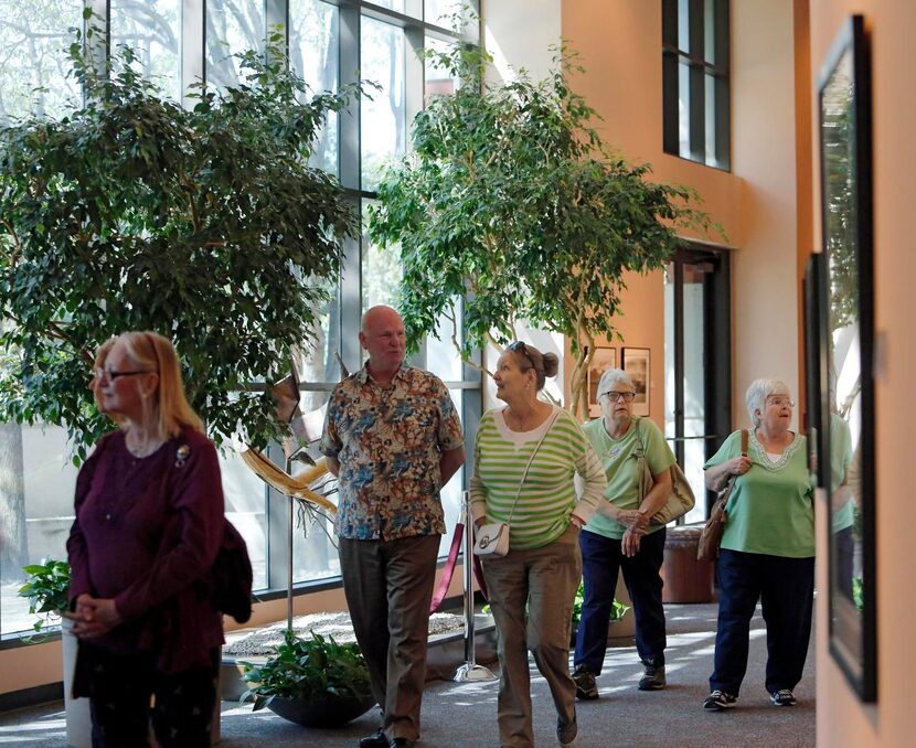 
A group of visitors looks through a gallery of Terry Cockerham’s photographs at the Irving...