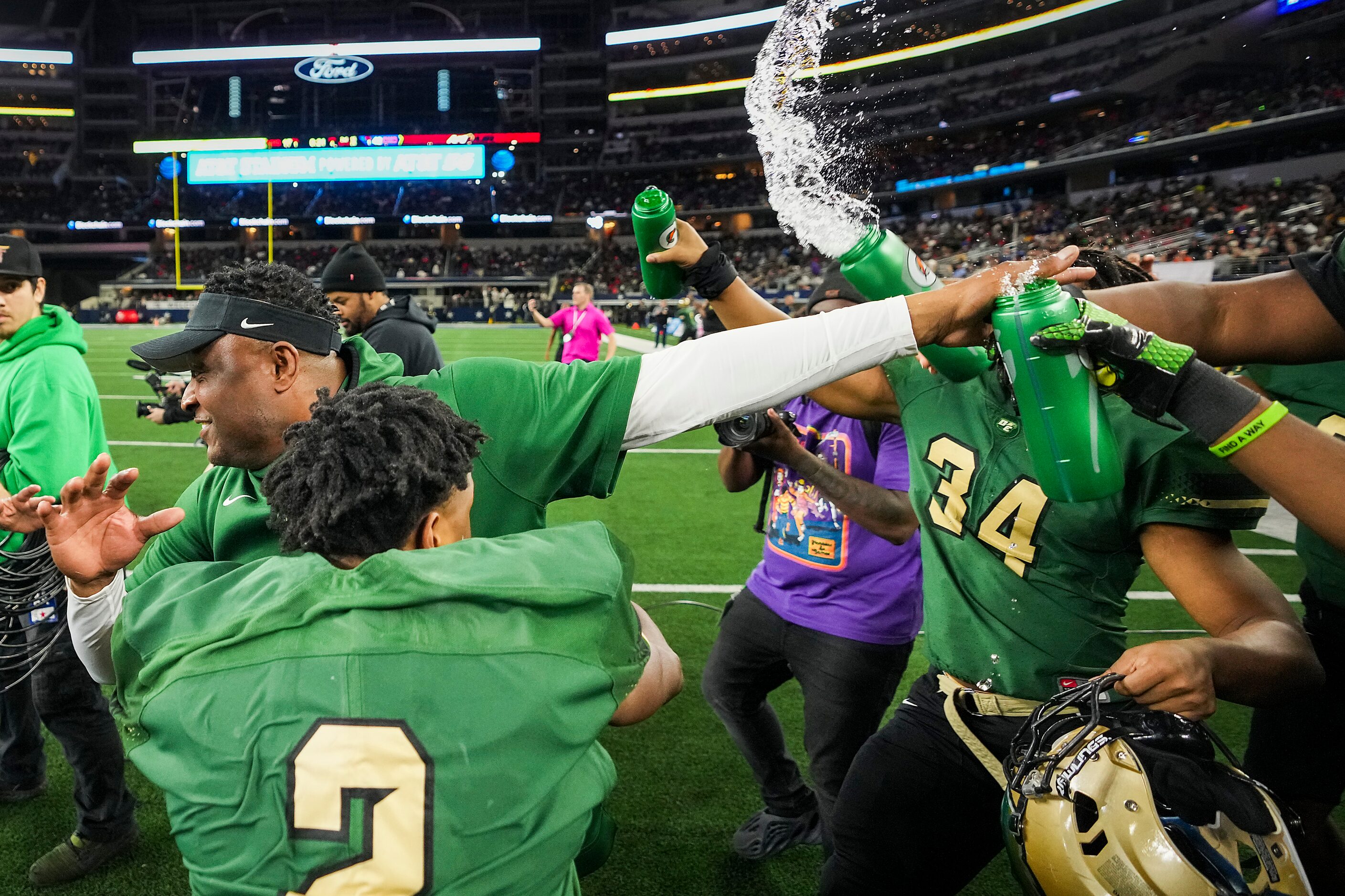 DeSoto head coach Claude Mathis is doused with water bottles by his players after a victory...