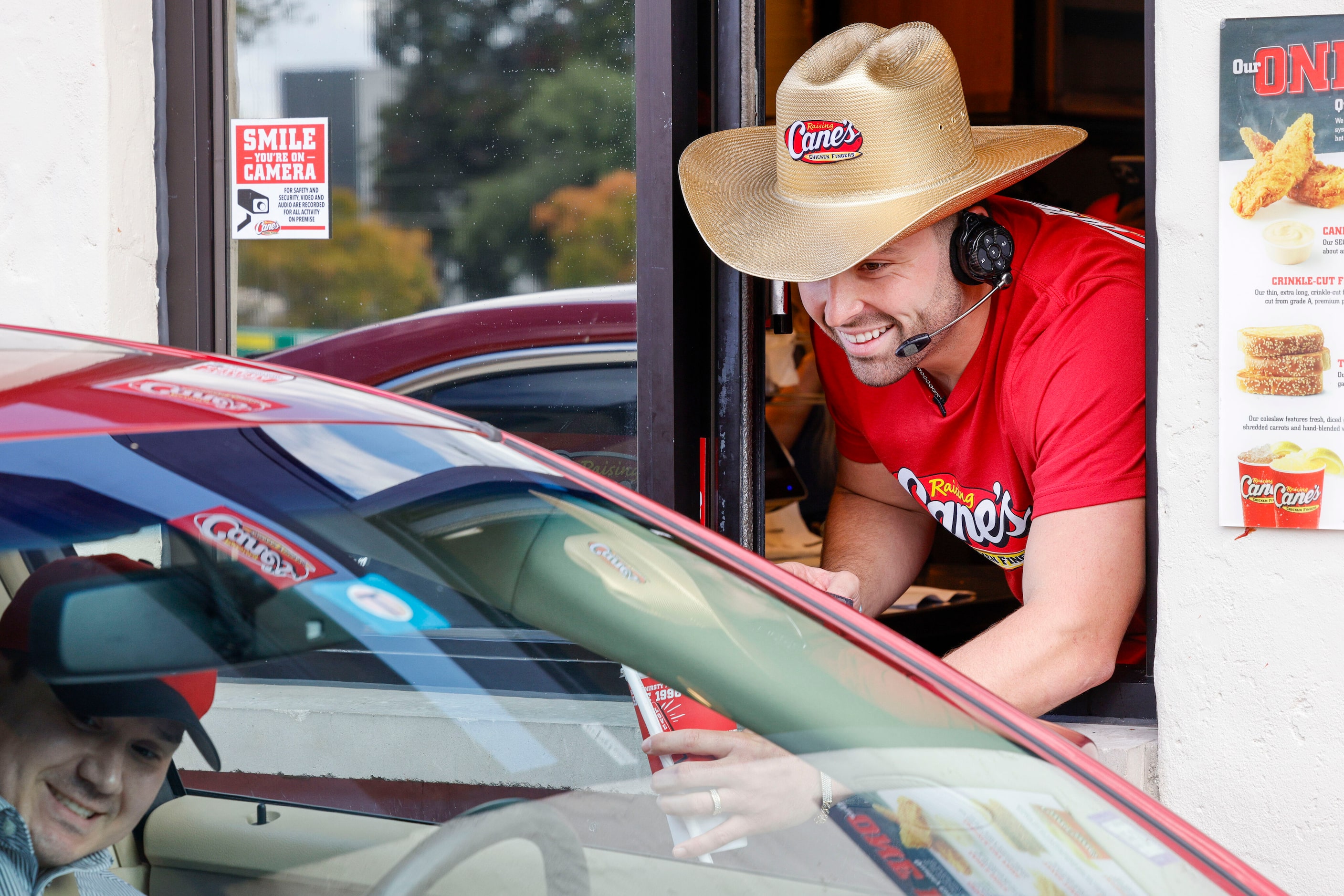 Former Oklahoma quarterback Baker Mayfield hands a customer their order as he works the...