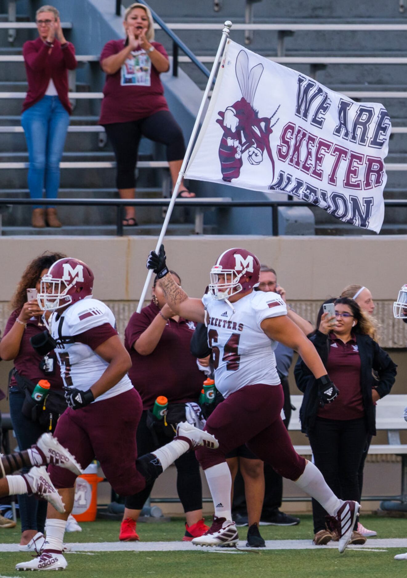 Mesquite offensive lineman J.D. Conley (64) carries the team flag as the Skeeters take the...
