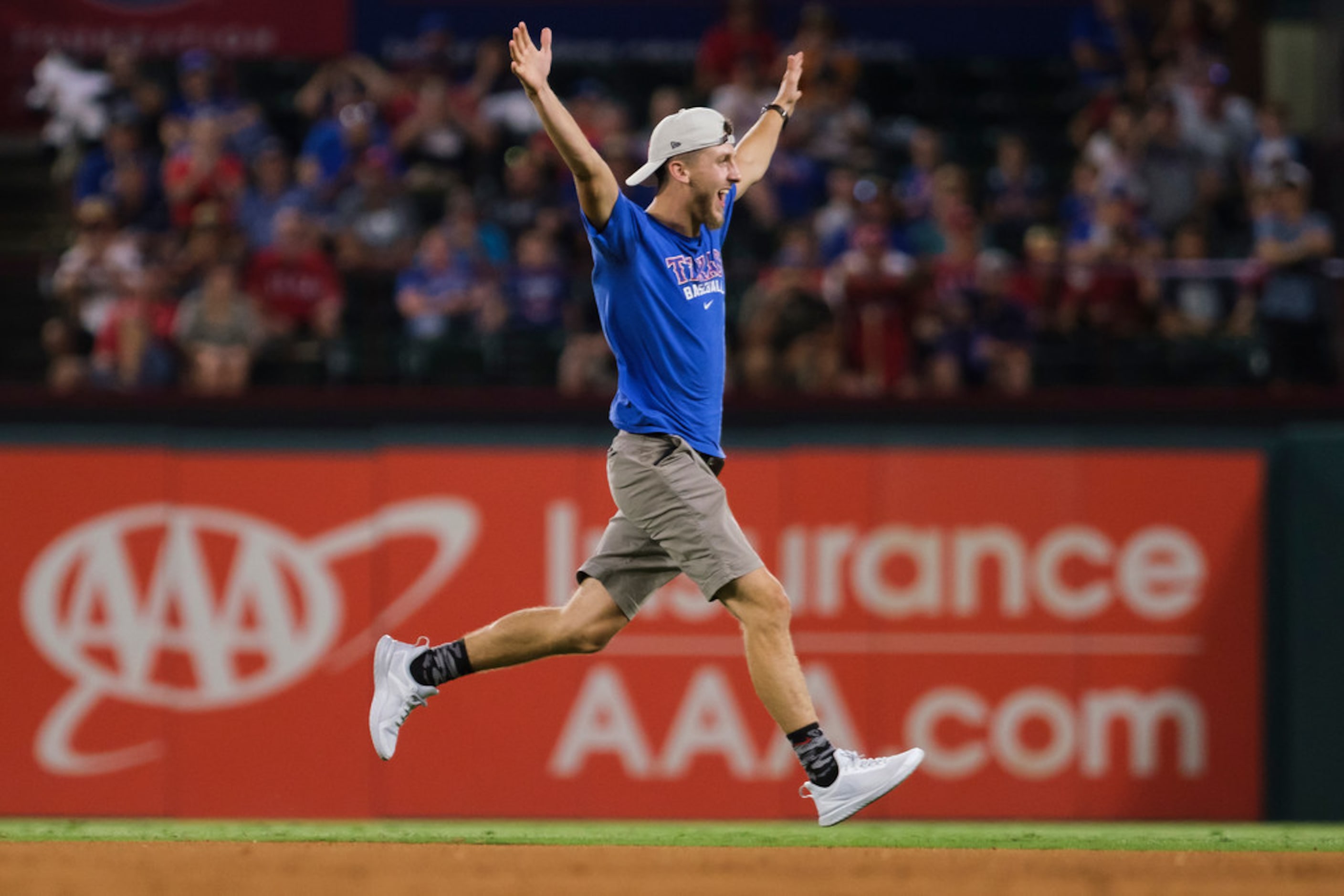 A fan runs on to the field during the ninth inning of a game between the Texas Rangers and...