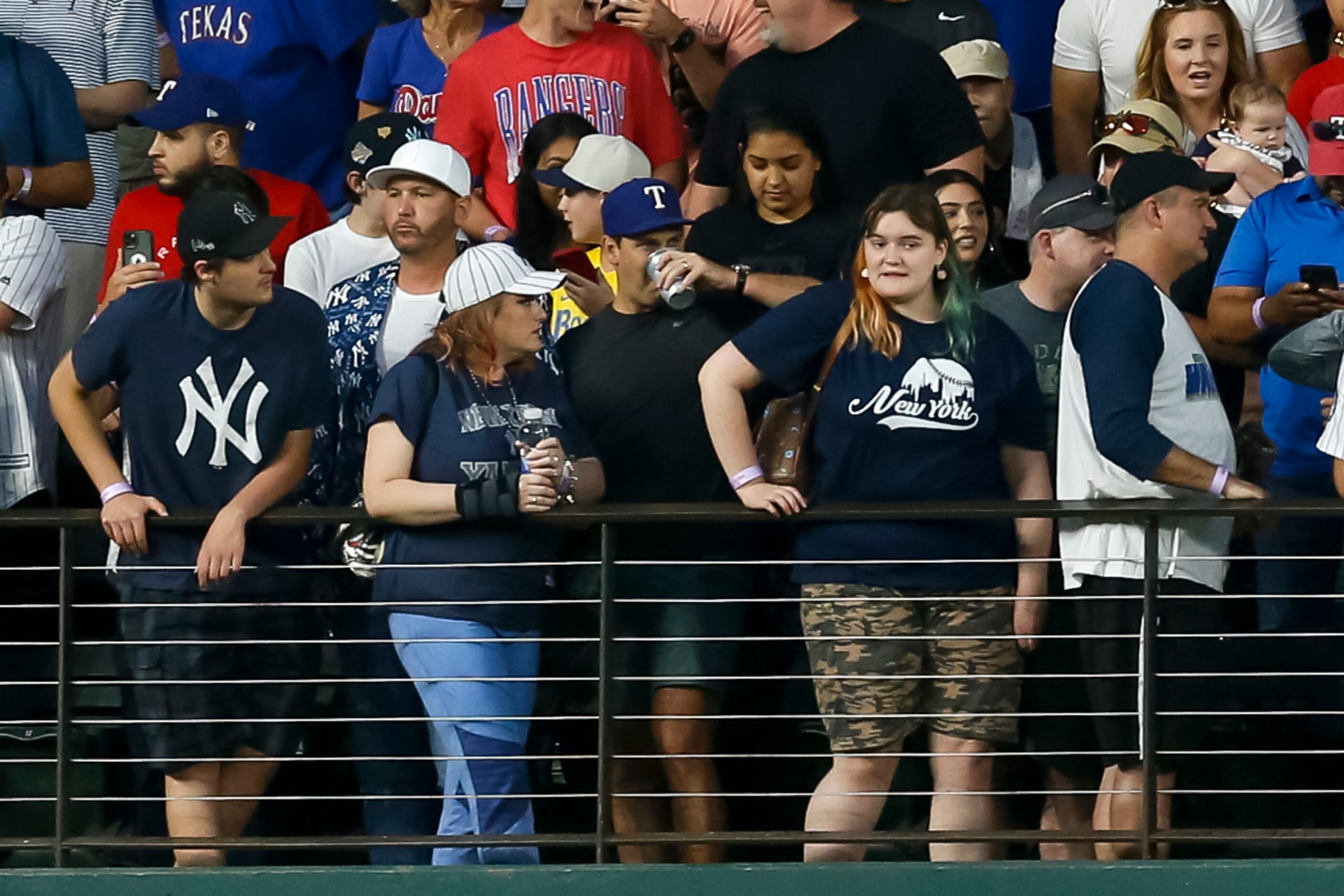 A Texas Rangers fan (center with blue hat) takes a drink after catching New York Yankees...