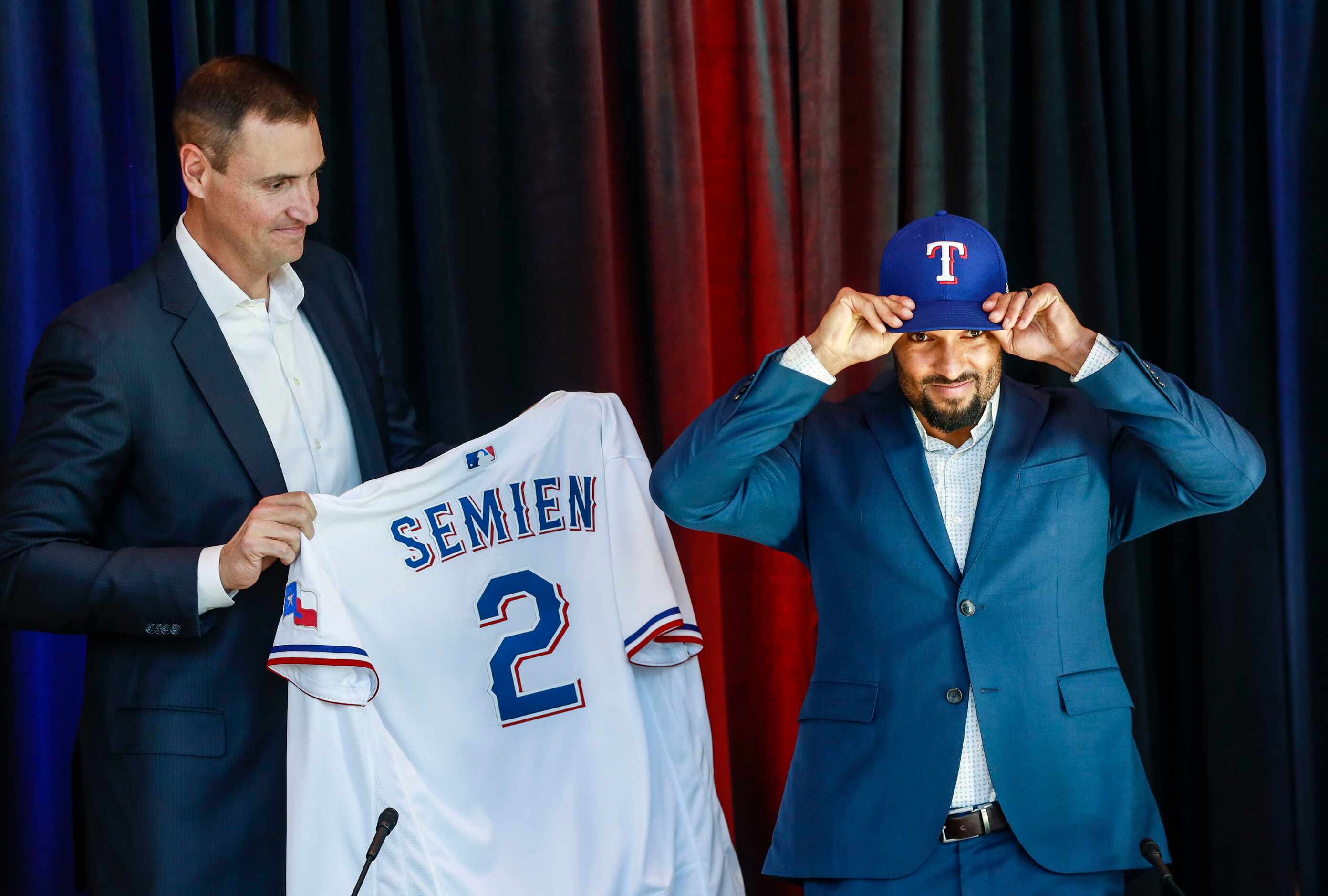 Marcus Semien puts on his Texas Rangers baseball hat at a news conference at Globe Life Park...