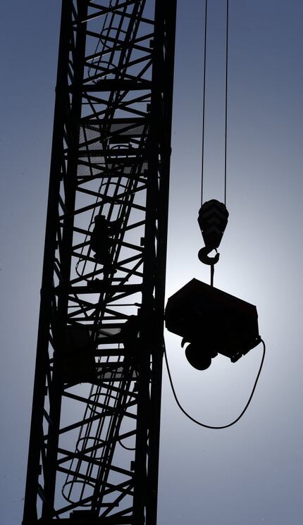 Workers climb a construction tower as a compressor is pulled up at the construction site of...