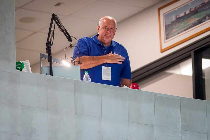Texas Rangers public address announcer Chuck Morgan places his hand over his heart from his...
