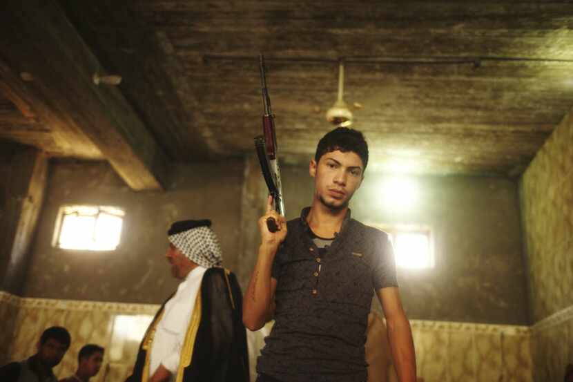A Shiite volunteer brandishes his weapon at a tribal meeting in Baghdad, June 13, 2014....