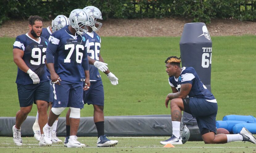 Dallas Cowboys defensive tackle David Irving (95), right, takes a knee as he watches his...