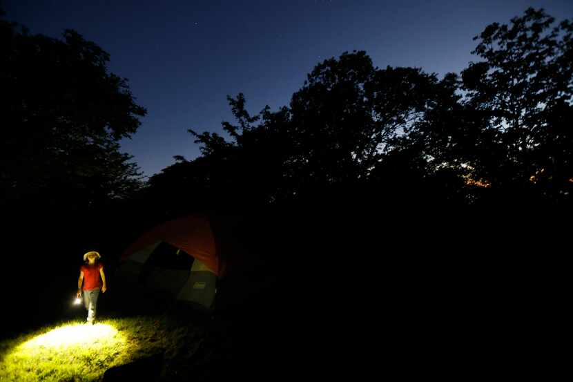 Adrian Edgar, 8, uses a flashlight to navigate her family’s campsite set up under the stars...