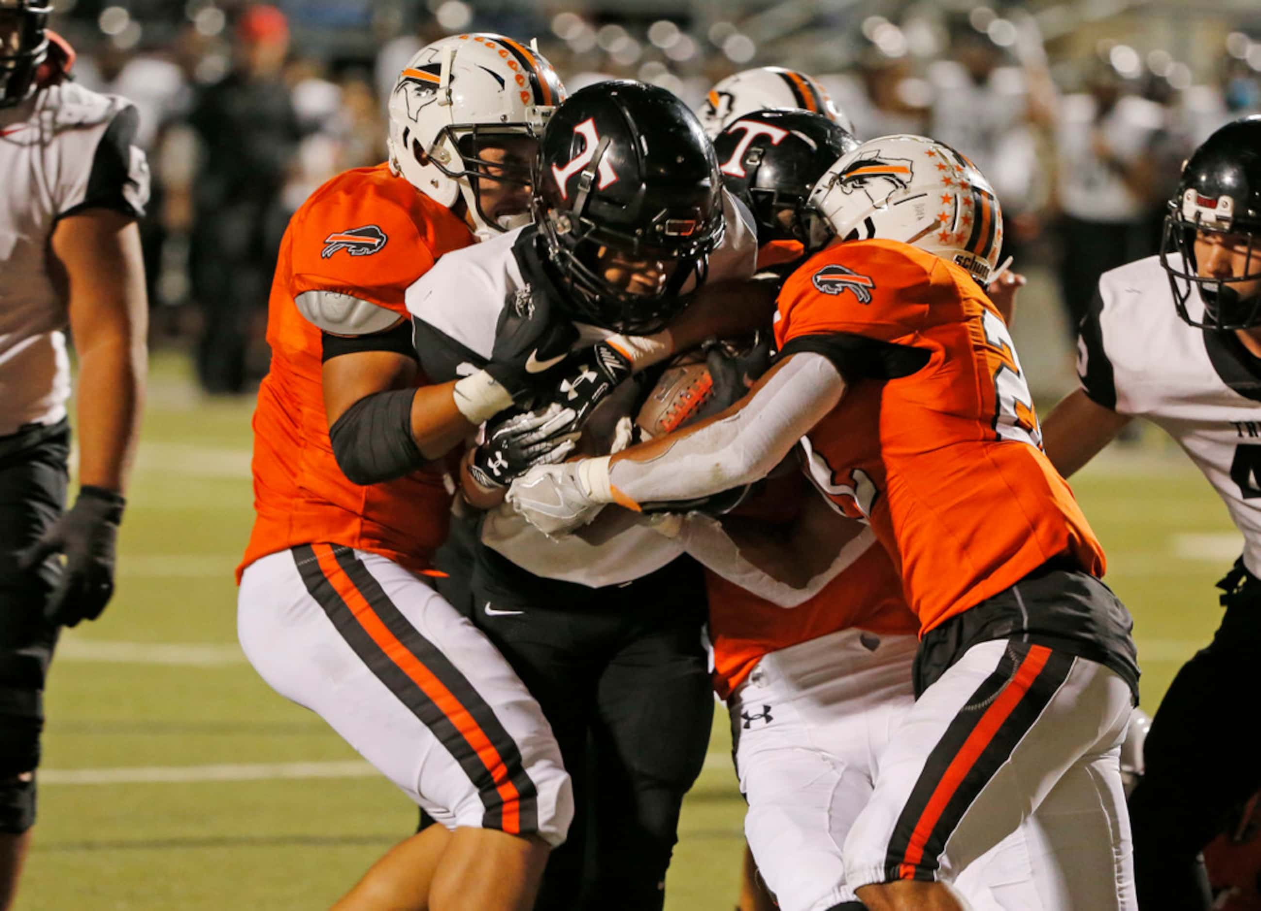 Haltom's Johnny Smith-Rider (22), right, strips the ball away from Trinity running back...