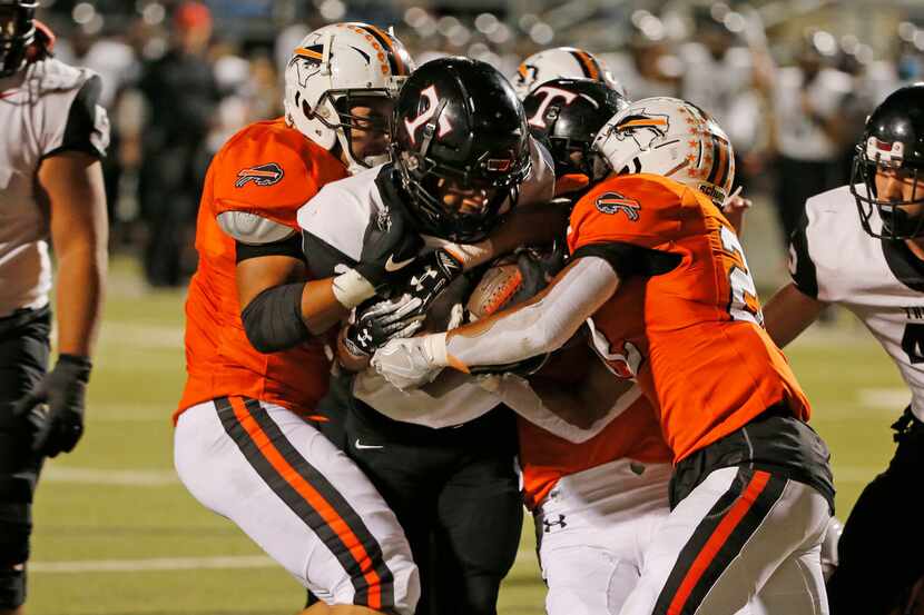 Haltom's Johnny Smith-Rider (right) strips the ball away from Euless Trinity running back...