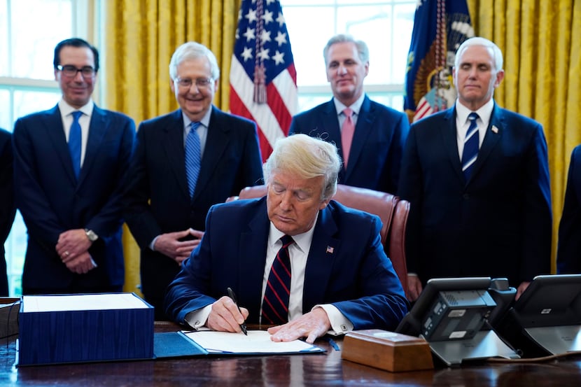 President Donald Trump signs the coronavirus stimulus relief package as from left, Treasury...