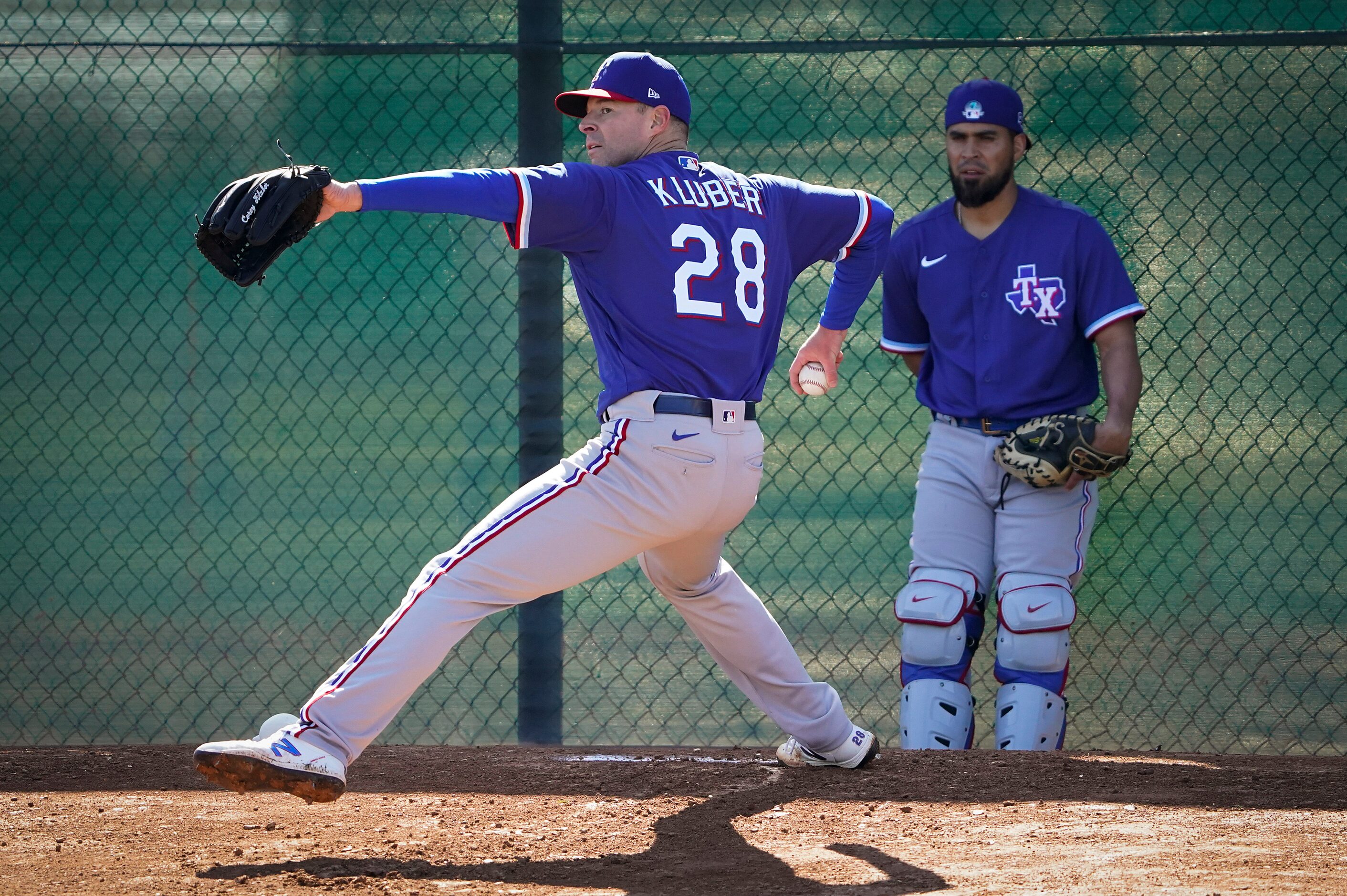 Texas Rangers pitcher Corey Kluber throws in the bullpen as catcher Robinson Chirinos looks...