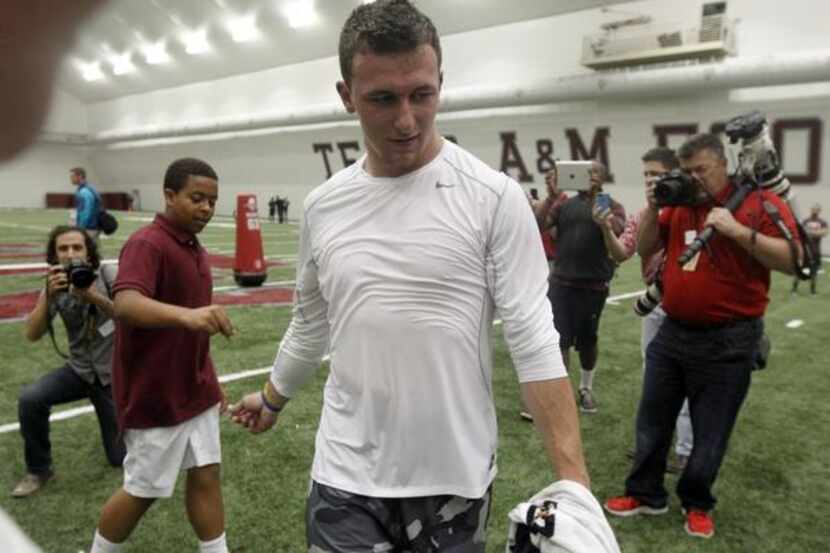 
Former Texas A&M QB Johnny Manziel, center, slaps hands with Chase Griffin, 14, after he...