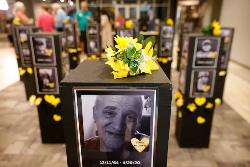 Photos of loved ones who died from COVID fill the Yellow Heart “More Than a Number” Memorial...