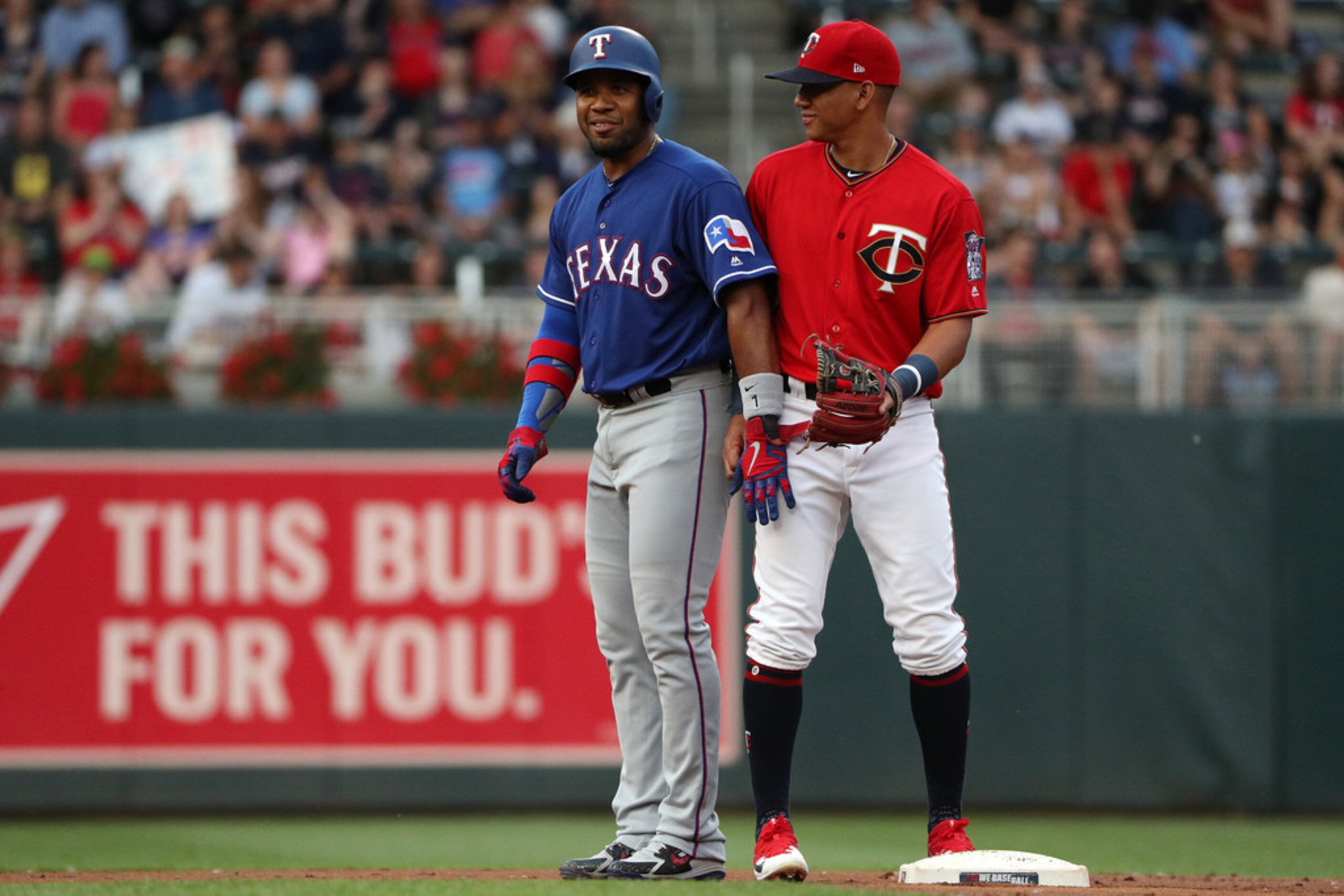 Minnesota Twins shortstop Ehire Adrianza, right, jokes with the Texas Rangers' Elvis Andrus,...