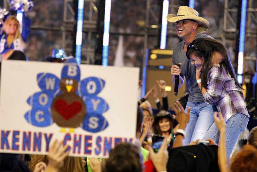Country superstar Kenny Chesney brings a lucky fan u p on stage during his halftime show...
