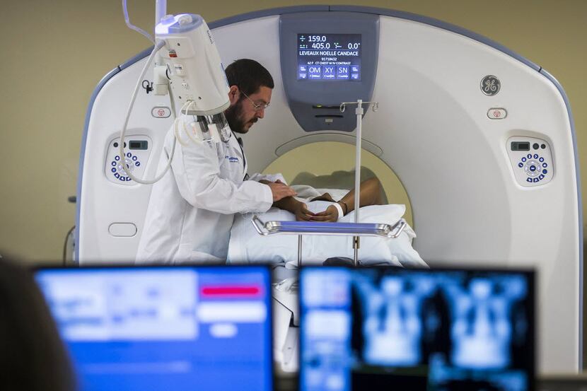 A breast cancer survivor has a CT scan with imaging technician Kenneth Colson at UT...