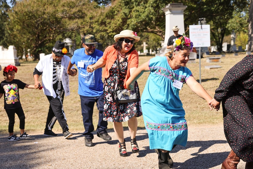 Cemetery administrator Monica Newbury (right) takes part in group dance during Day of the...