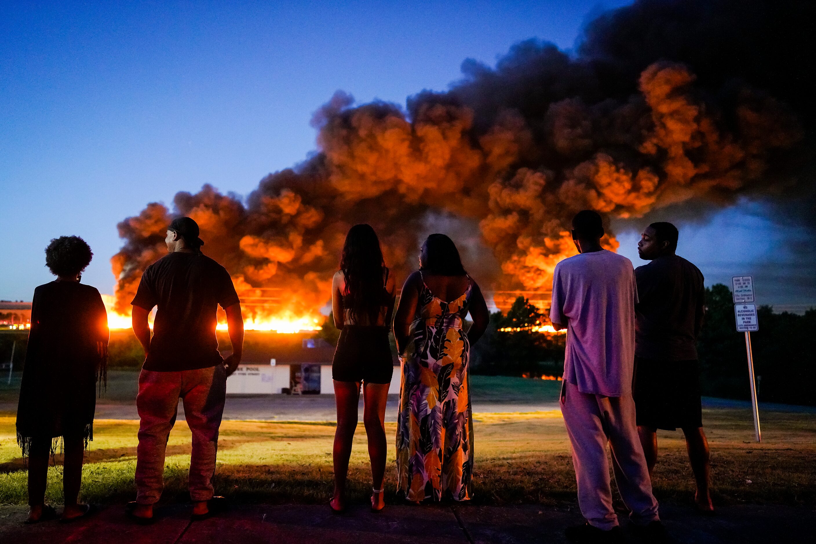 A plume of smoke rises over people gathered in Tyre Park to watch fire crews battle a...