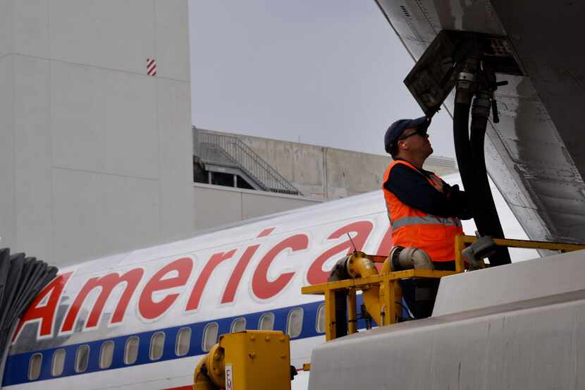  A ground crew worker fuels an American Airlines jet at Miami International Airport. in this...