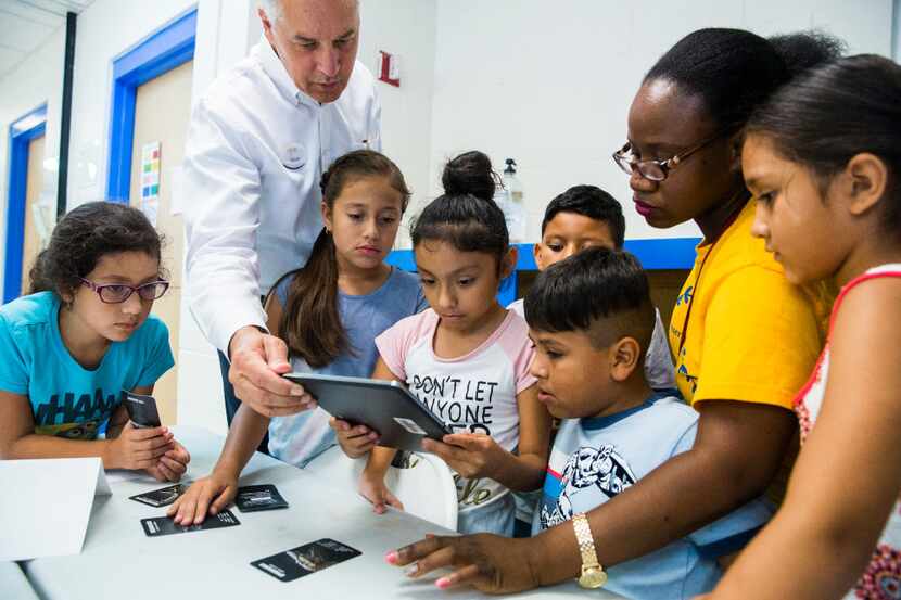 CEO Dave Woodyard, second from left, helps third graders with a 4D dinosaur tablet activity...