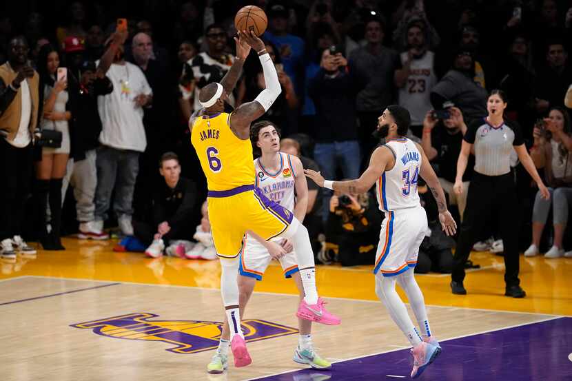 Los Angeles Lakers forward LeBron James, left, scores to pass Kareem Abdul-Jabbar to become...