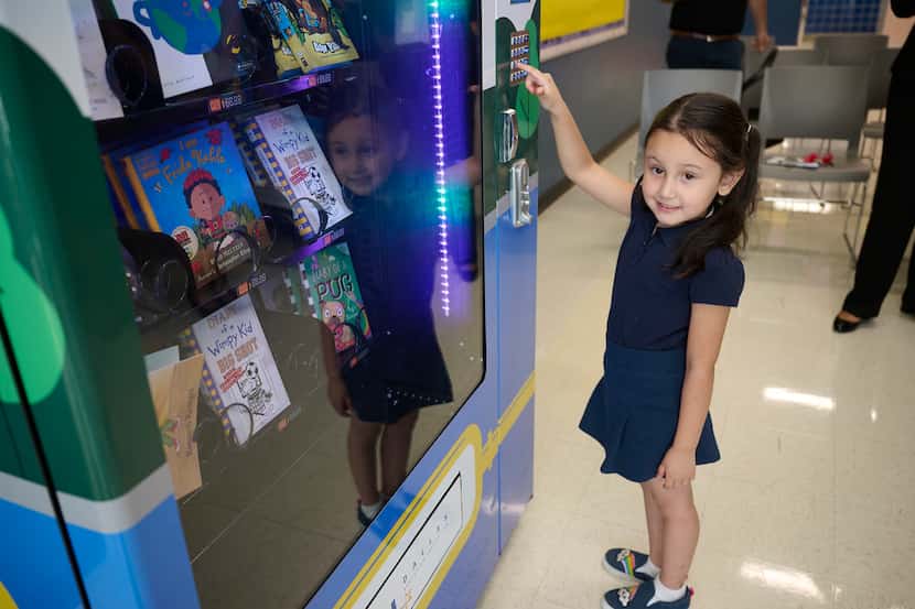 Kindergartner student Clarissa Alejandre uses a book vending machine that was donated to the...