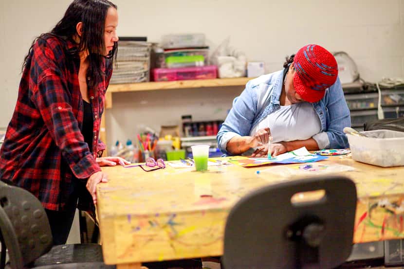 Artist and educator Jessica Bell looks on as community member Deirdre Harris paints at an...