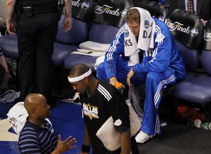 FILE - Dirk Nowitzki (41) sits during a timeout as the rest of the team huddles on the court...