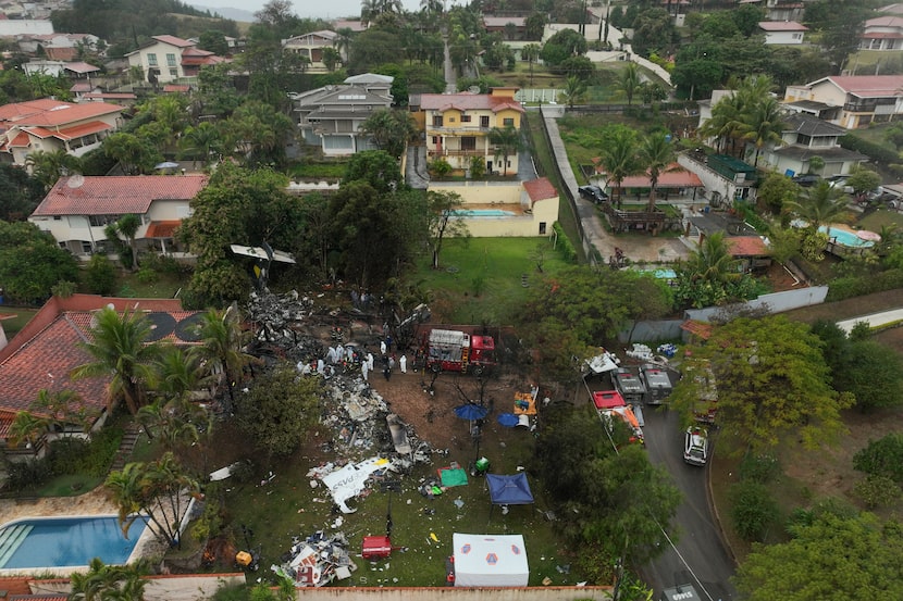 Firefighters and rescue teams work at the site in a residential area where an airplane with...