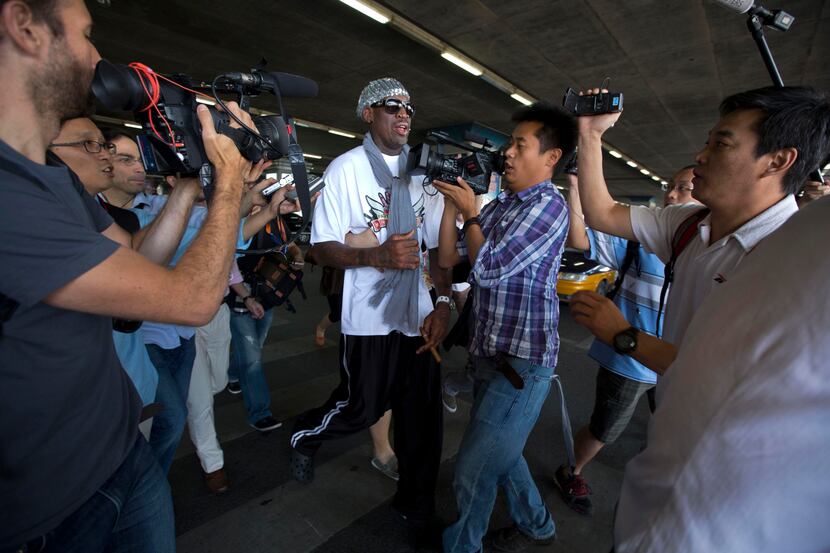 Retired NBA star Dennis Rodman, center, runs into a cameraman as he tries to get away from...
