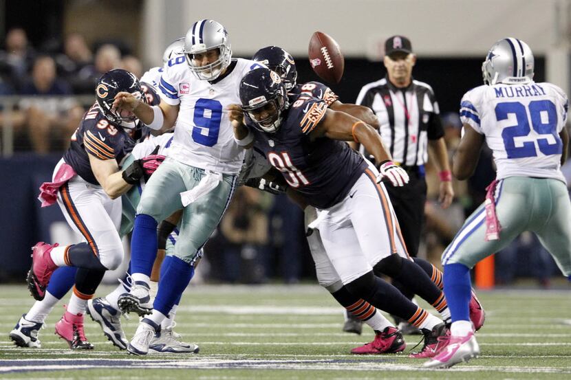 Dallas Cowboys quarterback Tony Romo (9) is hit by Chicago Bears defensive tackle Amobi...
