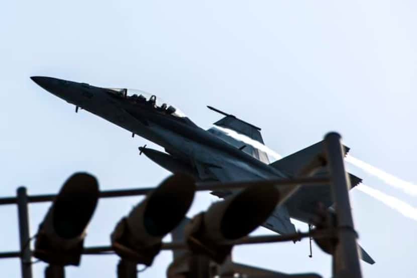 
An F/A-18F Super Hornet flies over the aircraft carrier USS George H.W. Bush in the Persian...