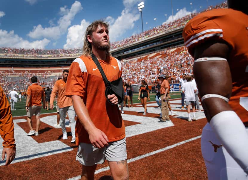With his arm in a sling, Texas Longhorns quarterback Quinn Ewers walks off the field...