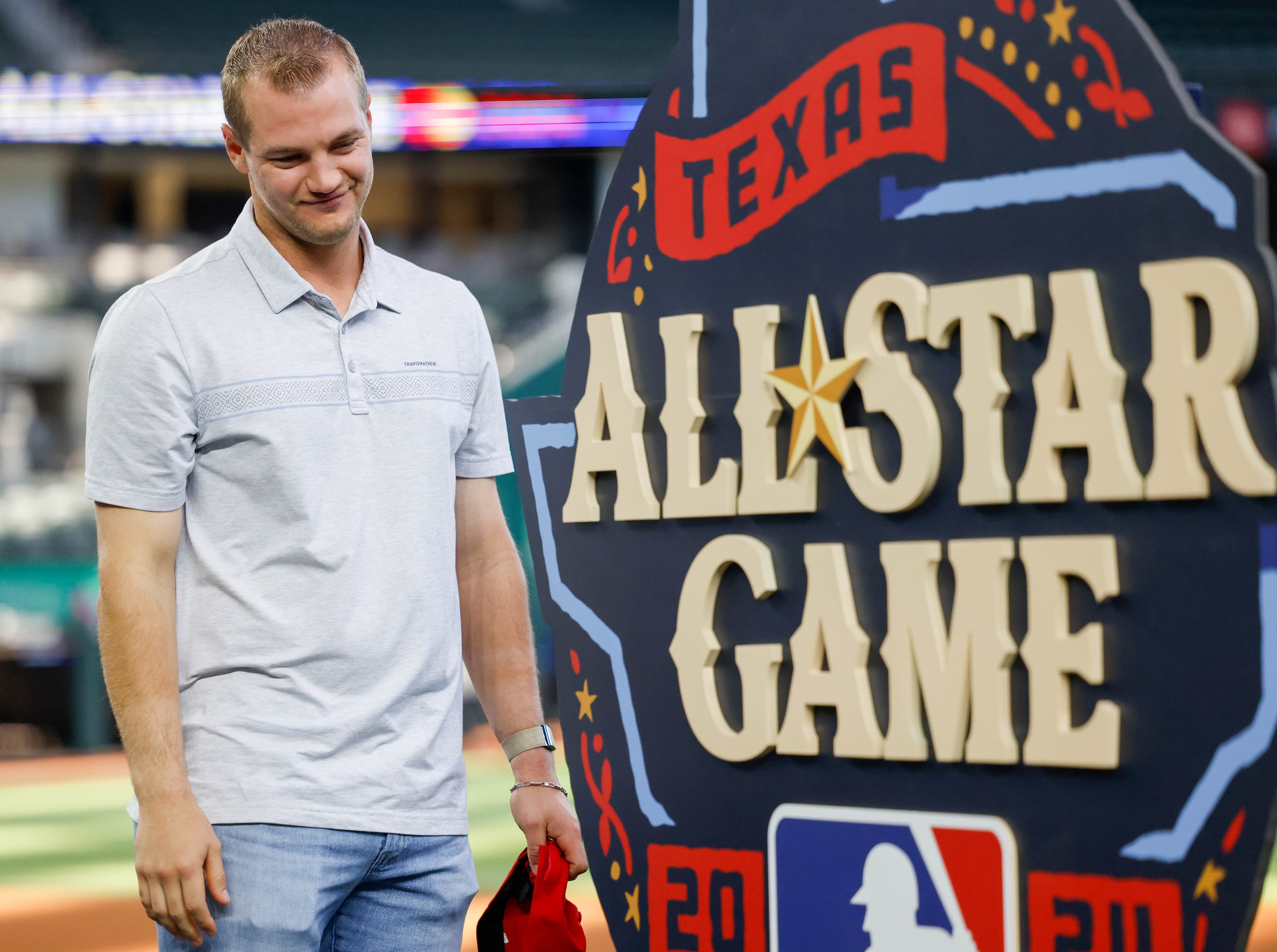 Rangers third baseman Josh Jung smiles as he looks at the official logo after helping with...