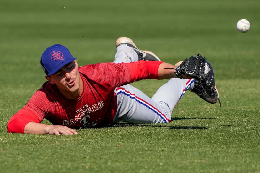 Outfielder Aaron Zavala dives for a ball in a fielding drill during a Texas Rangers minor...