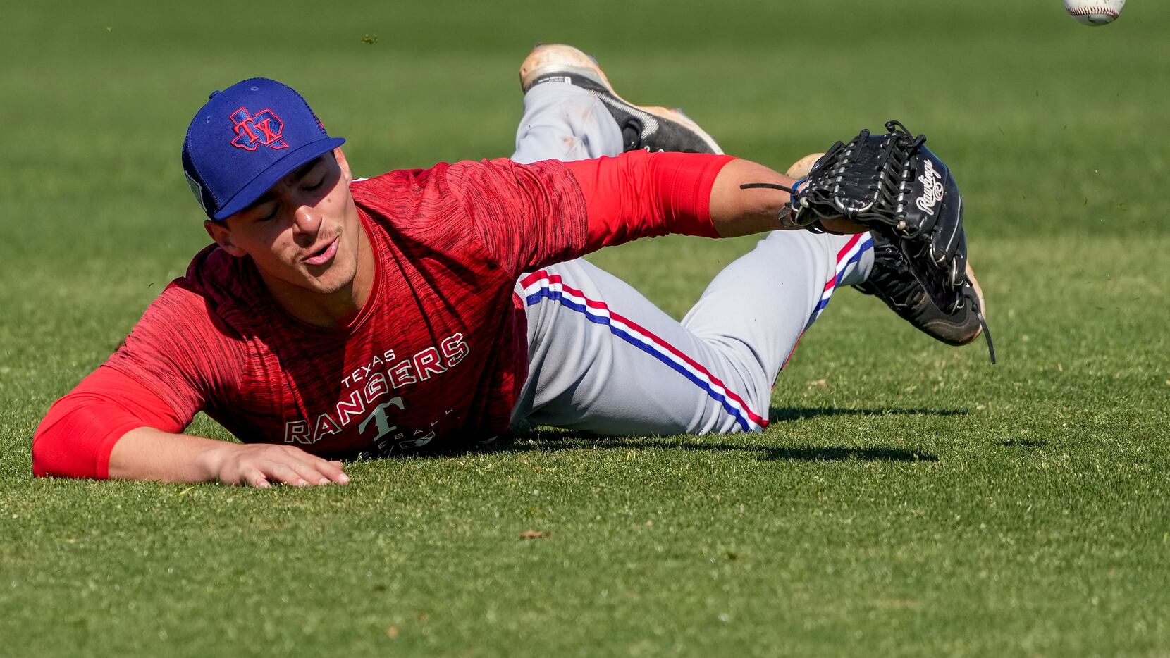 Outfielder Aaron Zavala dives for a ball in a fielding drill during a Texas Rangers minor...
