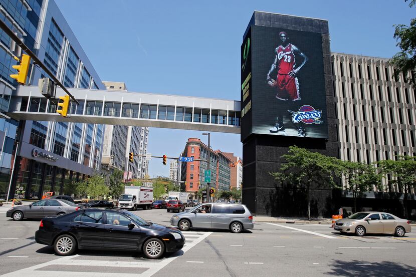 Motorists on East 9th Street in Cleveland pass a large electronic billboard featuring NBA...