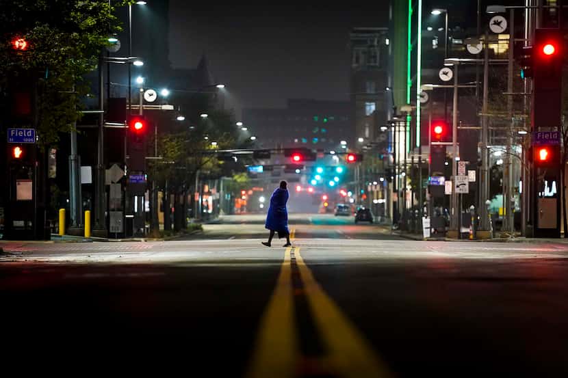 A solitary figure crosses the empty intersection of Main and Field streets in downtown...