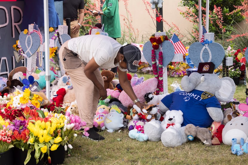 Cheryl Jackson helps tidy up the memorial honoring the victims of a mass shooting at the...