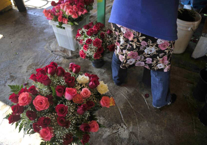 Gloria Jaimes appropriately wears a flower dress for the day as she works to arrange...